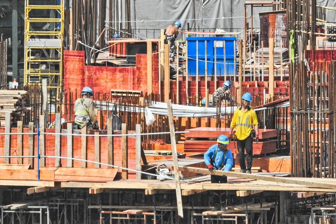 Construction workers in safety gear building a multi-story structure.